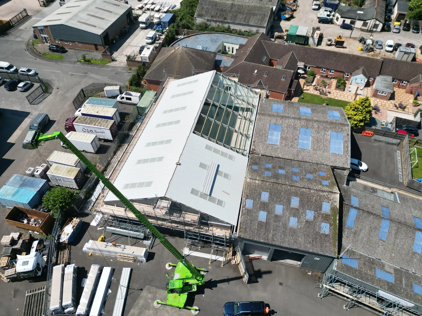 New roof panels going on beside the original asbestos cement roofs at a motor company