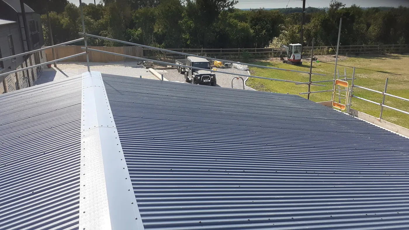 Corrugated roof sheets and ridge detail being installed