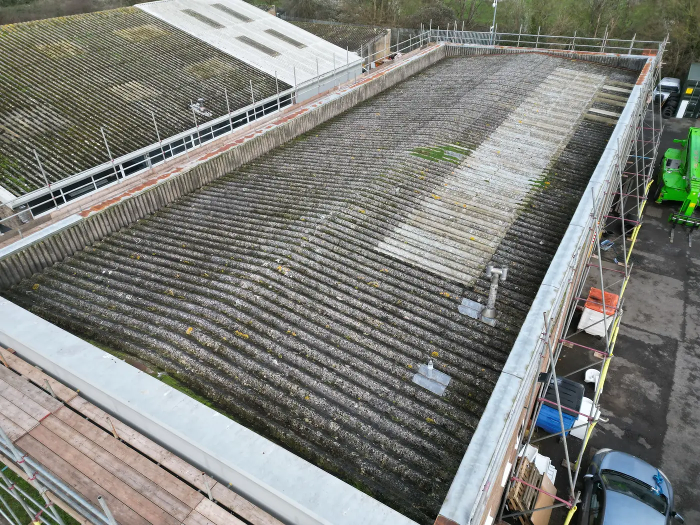 Weathered asbestos cement roof on a commercial unit, seen from above before replacement